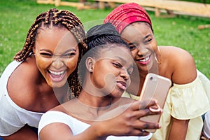 Portrait of three beautiful african-american women afro braids dreadlocks and turban taking pictures of yourself on the
