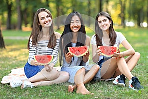 Portrait of three beautiful girls with slices of watermelon outdoors