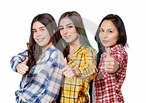 Portrait of three beautiful young happy females smiling joyfully showing thumbs up isolated on white