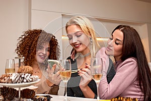 Portrait of three beautiful young women eating japanese food and drinking wine at home.
