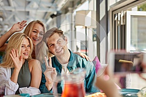 Portrait of three best friends sitting in cafe, taking photo