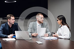 Portrait of three co-workers discussing business plan in office