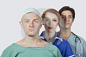 Portrait of three confident medical practitioners against gray background