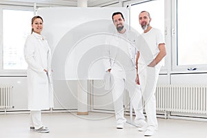 portrait of three doctors, standing in front of a whiteboard