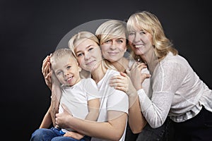 Portrait of three generations of women and a little boy. Grandmother, mother, daughter and son in white T-shirts. Love and