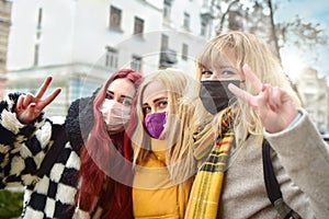 Portrait of three girls with protected wearing masks, making the Two Finger Peace Sign Hand Gesture . Concept of happiness and