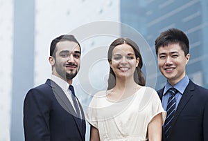 Portrait of three smiling business people, outdoors, business district