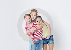 Portrait of three smiling girls at white studio background