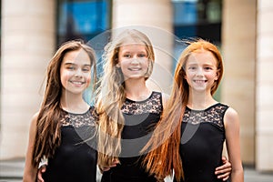 Portrait of three teenage girls with loose hair, blonde, redhead and brunette Summer on street. Vloses develop in wind