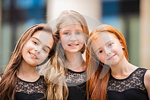 Portrait of three teenage girls with loose hair, blonde, redhead and brunette Summer on street. Vloses develop in wind