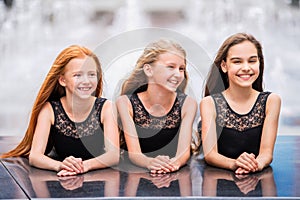 Portrait of three teenage girls with loose hair, blonde, redhead and brunette Summer on street. Vloses develop in wind