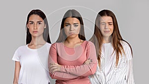 Portrait Of Three Upset Young Women Standing Isolated Over Grey Background