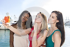 Portrait of three women taking duck-face selfies with a smartphone. photo