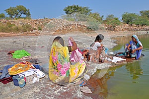 CHITTORGARH, RAJASTHAN, INDIA - DECEMBER 13, 2017: Portrait of three women washing clothes and dressed with colorful saris next to