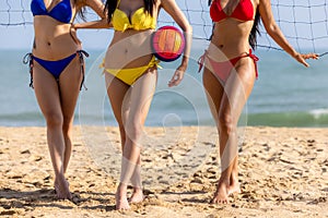 Portrait of Three Young Women in bikini Standing by a Volleyball Net on the beach