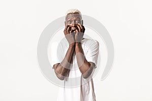 Portrait of thrilled and tempted african-american blond guy, trembling from excitement, standing white background