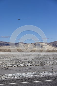 Portrait of tiny black drone flying away towards sand dunes of Sand Mountain OHV park photo