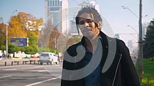 Portrait of tired African-American guy with dreadlocks nervously standing near road.