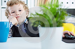 Portrait of tired business child wearing formal shirt and tie. Cute little boy covering his mouth with hands, imitating