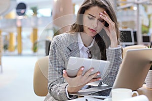 Portrait of tired business lady working with touchpad in office