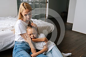 Portrait of tired cute little girl with closed eyes and loving caring mother comforting offended sad child daughter