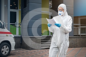 Portrait of tired exhausted female doctor, scientist or nurse wearing face mask and biological hazmat ppe suit reading who