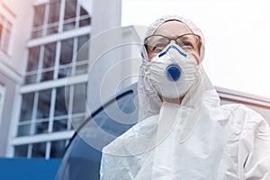 Portrait of tired exhausted pensive female doctor, scientist or nurse wearing face mask and biological hazmat ppe suit looking