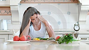 Portrait tired female housewife having headache touching head making circular massage while cooking
