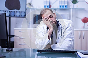 Portrait of tired male doctor sleeping on his desk after a long day at the hospital