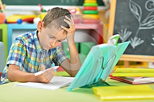 Portrait of schoolboy doing homework in classroom