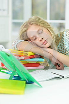 Portrait of tired schoolgirl sleeping at desk after studying at home