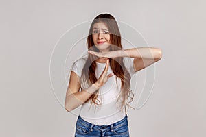 Portrait of tired upset woman showing time out gesture, stop or limit hand sign, warning of deadline