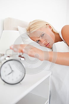 Portrait of a tired woman awaken by an alarmclock