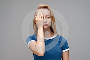 Portrait of tired woman with long chestnut hair in casual red sweater covering her eyes with hand. Weariness and people