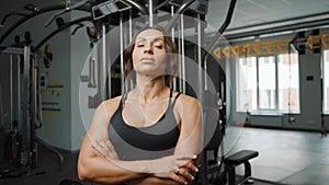 Portrait of tired woman in sportswear in gym possing at camera