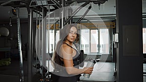 Portrait of tired woman in sportswear with sports bottle in gym