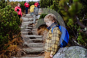 Tired boy resting during difficult hike in a autumn mountains.