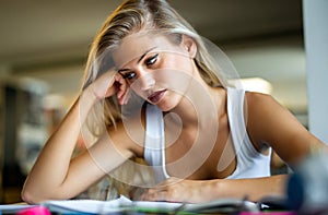 Portrait of tired young female studying in a library. Education study teenager concept