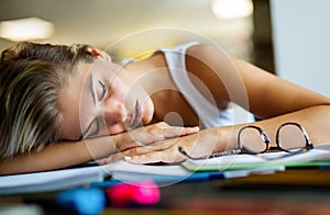 Portrait of tired young female studying in a library. Education study teenager concept