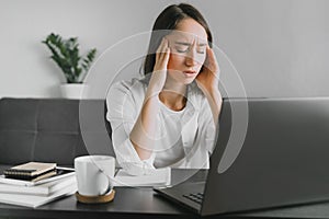 Portrait of tired young woman with laptop at the home office.