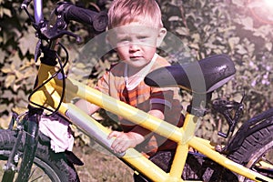Portrait of a toddler with a bicycle on a sunny day.