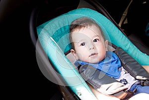 Portrait of toddler boy in car seat. Little smiling baby child fastened with a seat belt portrait of adorable happy baby boy