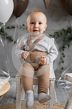 Portrait of a toddler boy on his first birthday, cute baby on a chair posing, background decoration.