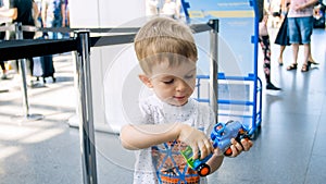 Portrait of toddler boy playing with toy car at airport terminal or railway station