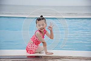 Portrait Toddler girl Kid smile laugh look at camera. Girl in pink swimsuit playful in swimming pool summer time with pink