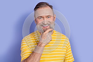 Portrait of toothy beaming good mood pensioner persone wear yellow t-shirt touching white gray beard isolated on violet photo