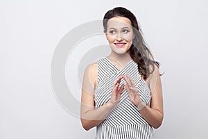 Portrait of toothy smiley beautiful young brunette woman with makeup and striped dress standing and looking away with cunning face