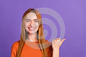 Portrait of toothy smiling foxy girl wearing orange t shirt point finger empty space stomatology clinic isolated on