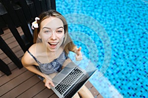 Portrait of top of happy female looking at camera with laptop on