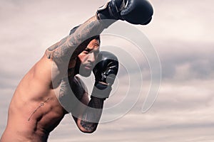 Portrait of tough male boxer posing in boxing gloves. Professional fighter ready for boxing match. Sportsman muay thai